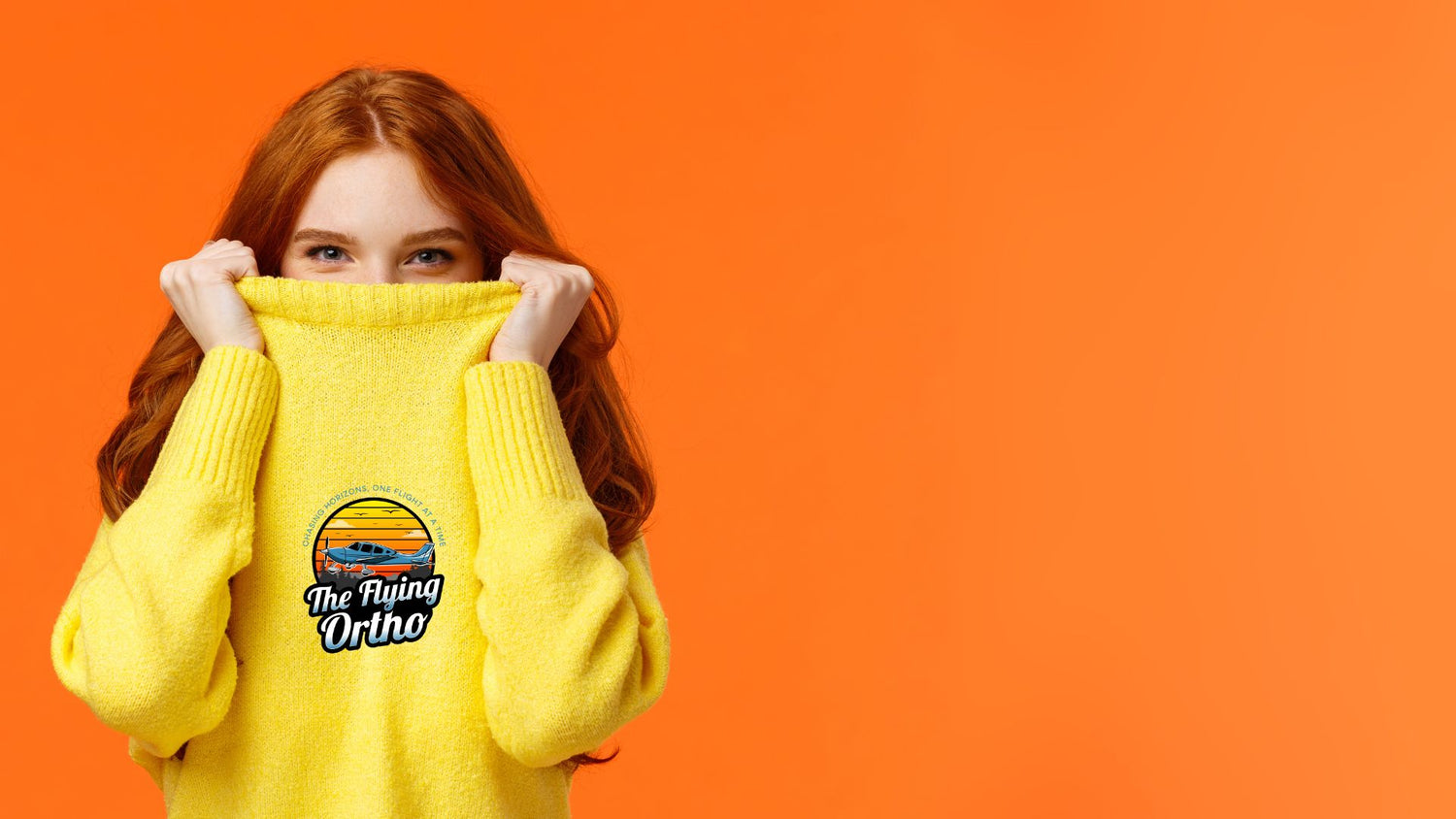Person wearing a yellow sweater with a logo on an orange background